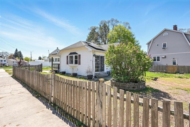 bungalow-style house featuring roof mounted solar panels and a fenced backyard