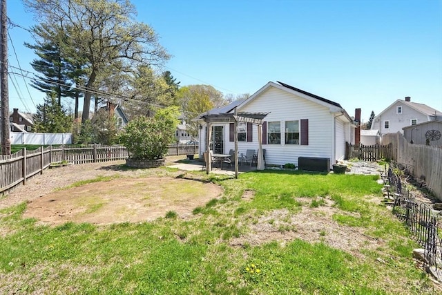 back of house with a fenced backyard, a pergola, a yard, and a patio area
