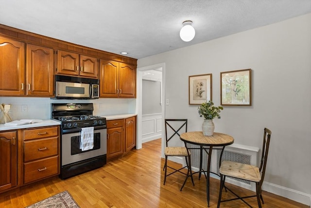 kitchen with stainless steel appliances, light wood finished floors, tasteful backsplash, light countertops, and brown cabinets