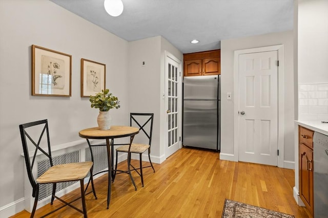 kitchen with appliances with stainless steel finishes, baseboards, brown cabinetry, light wood-style floors, and recessed lighting