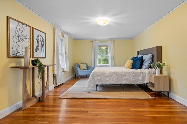 bedroom with wood finished floors, baseboards, radiator heating unit, and ornamental molding