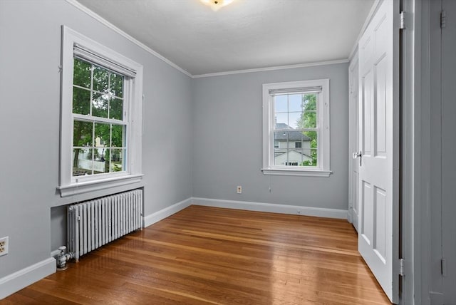 unfurnished bedroom with radiator heating unit, wood finished floors, crown molding, and baseboards