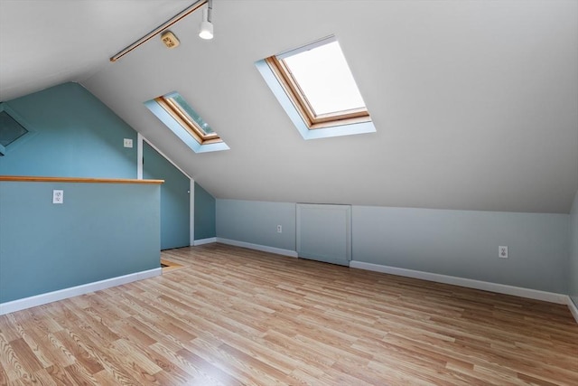 additional living space with a skylight, lofted ceiling, wood finished floors, and baseboards