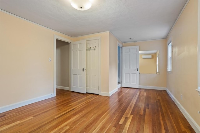 unfurnished bedroom featuring wood finished floors, baseboards, a closet, and a textured ceiling