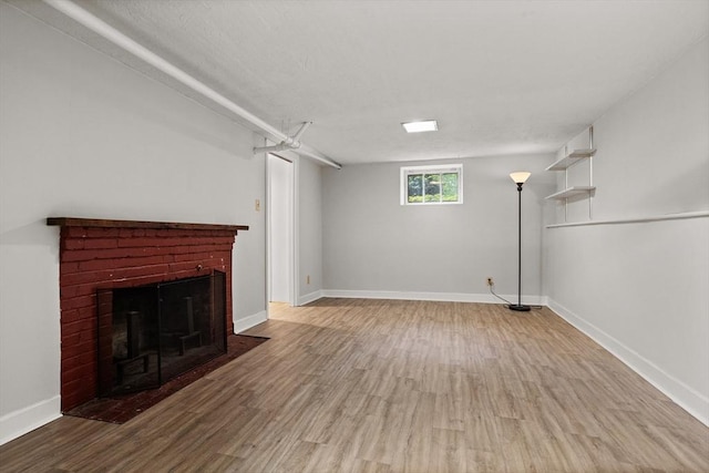 basement featuring wood finished floors, a brick fireplace, and baseboards