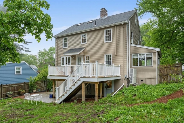 rear view of house featuring stairway, fence, a chimney, a deck, and a patio area