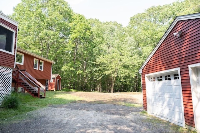 8 Adams Rd, Hubbardston, MA 01452 - garage featuring a forest view, asphalt driveway, and a shed