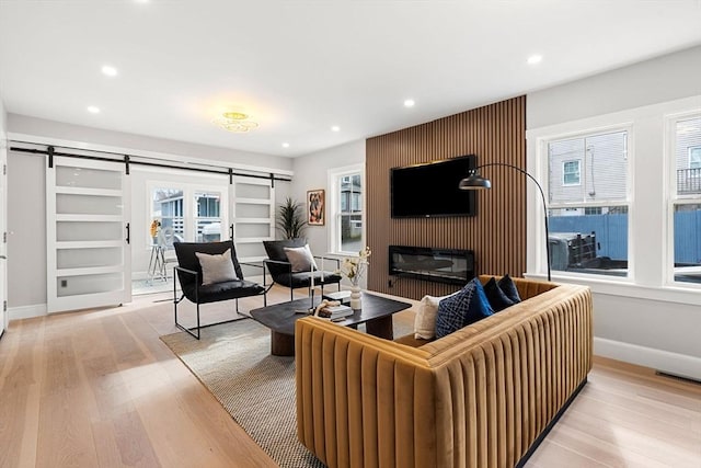 living room featuring a healthy amount of sunlight, a barn door, and light hardwood / wood-style flooring