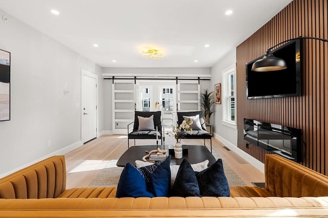 living room featuring a barn door and light hardwood / wood-style flooring