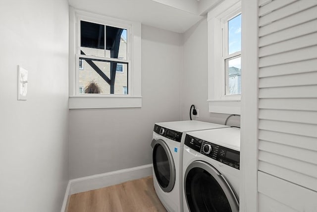 clothes washing area with independent washer and dryer, light hardwood / wood-style flooring, and a wealth of natural light