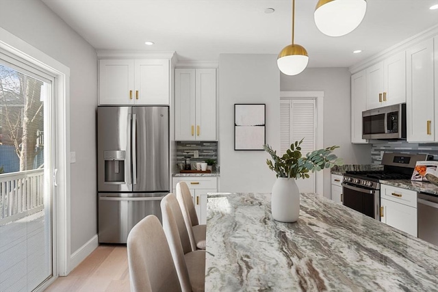 kitchen featuring white cabinetry, decorative light fixtures, stainless steel appliances, light stone countertops, and decorative backsplash