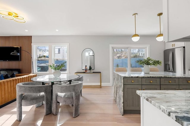 kitchen featuring gray cabinets, pendant lighting, white cabinets, light stone counters, and stainless steel refrigerator with ice dispenser