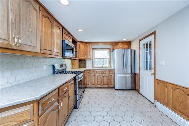 kitchen featuring sink, appliances with stainless steel finishes, baseboard heating, and decorative backsplash