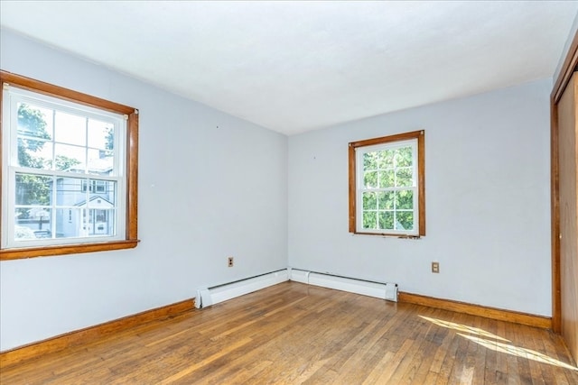 unfurnished room featuring baseboard heating and hardwood / wood-style flooring