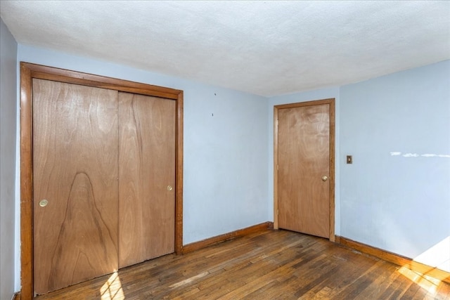 unfurnished bedroom with a textured ceiling, a closet, and dark hardwood / wood-style flooring