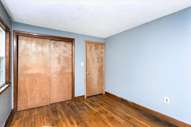 unfurnished bedroom with dark hardwood / wood-style flooring and a closet