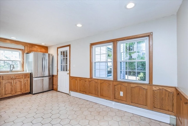 kitchen with stainless steel fridge, baseboard heating, sink, and a wealth of natural light