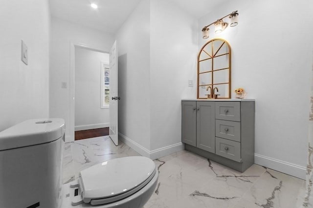 bathroom featuring marble finish floor, toilet, and baseboards