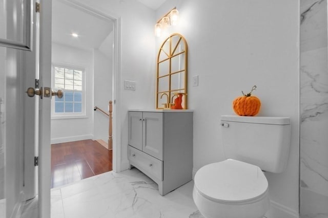 bathroom with baseboards, toilet, marble finish floor, and vanity