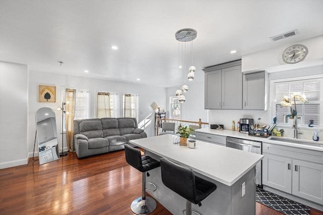 kitchen with visible vents, gray cabinets, a kitchen breakfast bar, dark wood finished floors, and light countertops