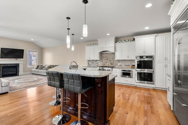 50 Sterling Rd, Needham, MA 02492 - kitchen featuring stainless steel appliances, open floor plan, tasteful backsplash, light wood-type flooring, and white cabinetry