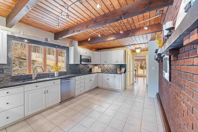 kitchen with backsplash, appliances with stainless steel finishes, white cabinets, and a sink