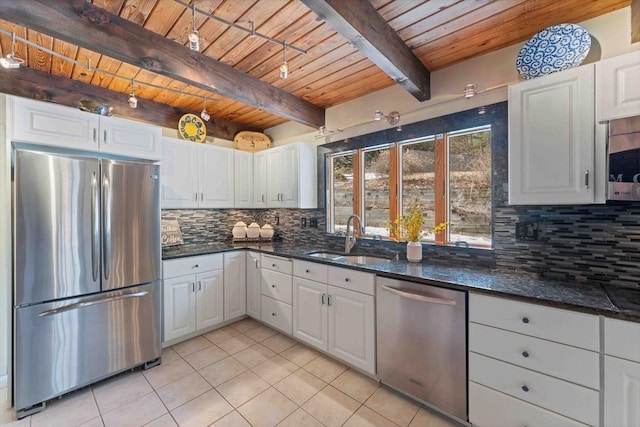 kitchen featuring a sink, backsplash, appliances with stainless steel finishes, white cabinets, and light tile patterned flooring