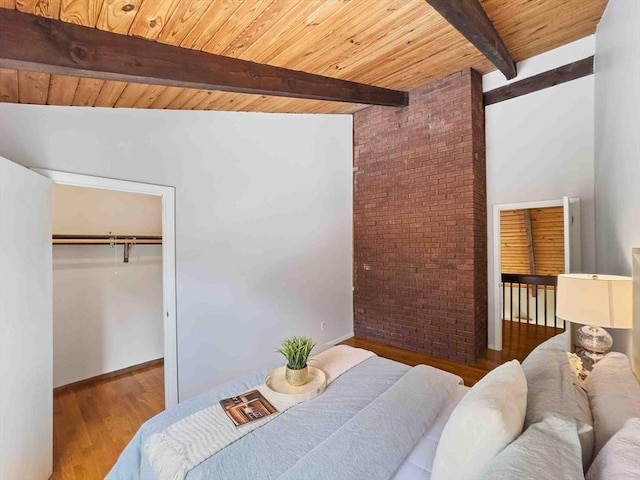 bedroom featuring brick wall, wood ceiling, beam ceiling, wood finished floors, and a closet