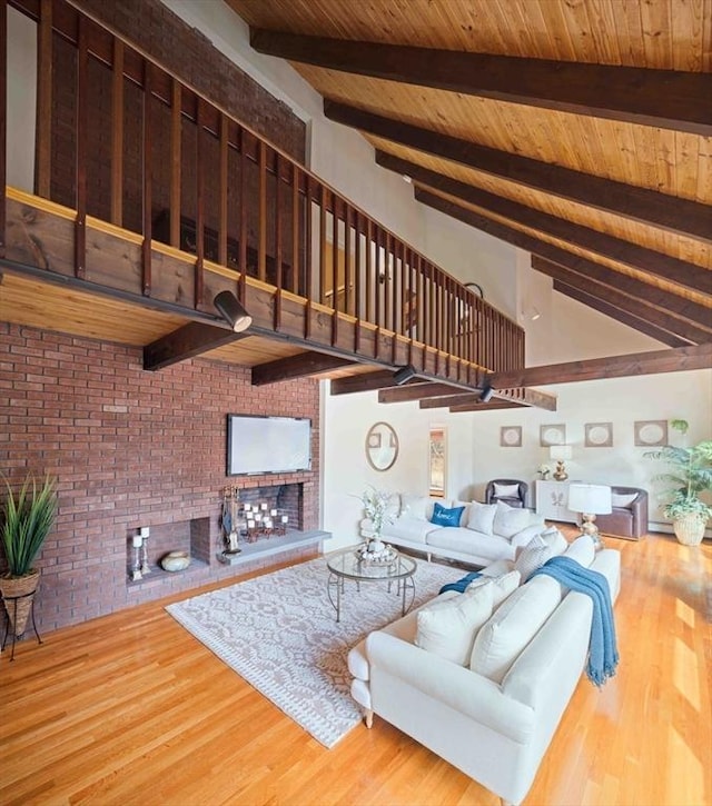 living area featuring brick wall, beamed ceiling, wooden ceiling, a fireplace, and wood finished floors