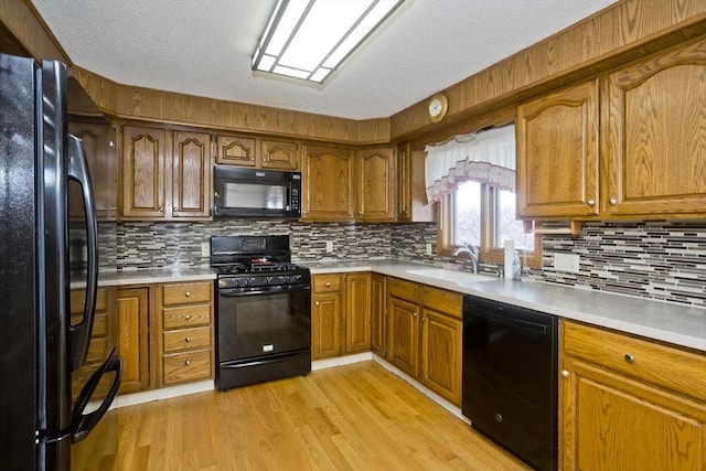 kitchen with a sink, light countertops, black appliances, and brown cabinets