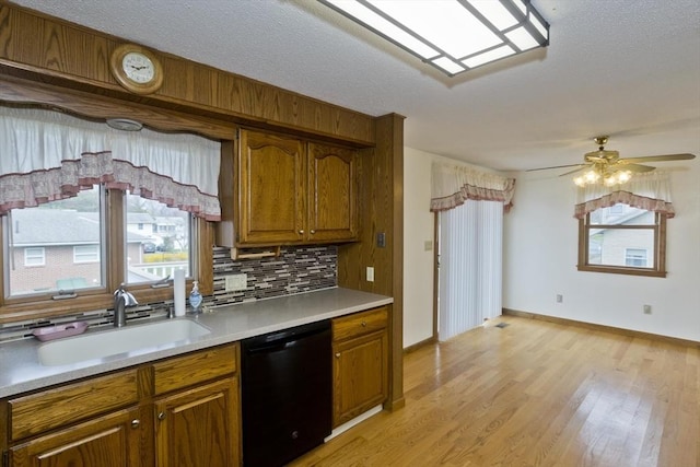 kitchen with a sink, light countertops, brown cabinetry, and black dishwasher
