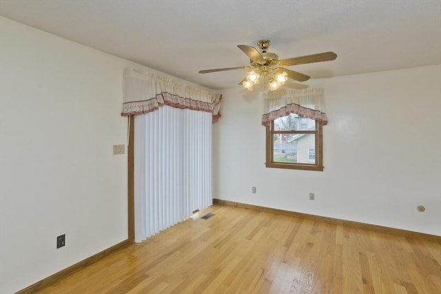 spare room featuring light wood-style floors, a ceiling fan, and baseboards