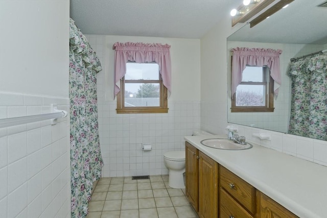 full bath featuring tile patterned flooring, a healthy amount of sunlight, toilet, and tile walls
