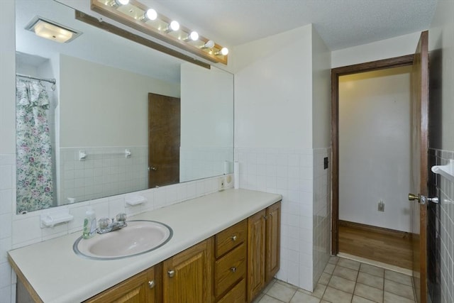 full bath with tile patterned flooring, a wainscoted wall, vanity, and tile walls