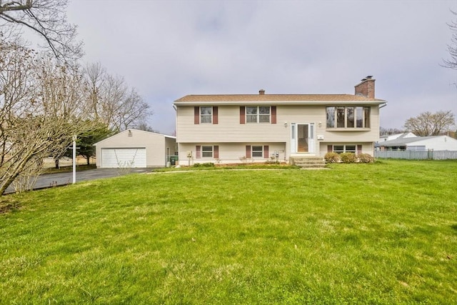 bi-level home featuring a chimney, a front yard, a garage, fence, and an outdoor structure