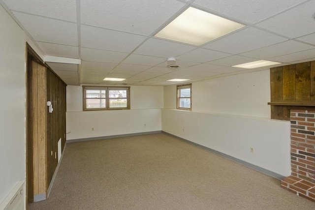 basement featuring baseboards, a drop ceiling, and carpet floors