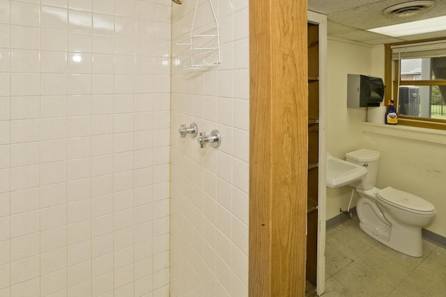 full bathroom with baseboards, toilet, tiled shower, and visible vents