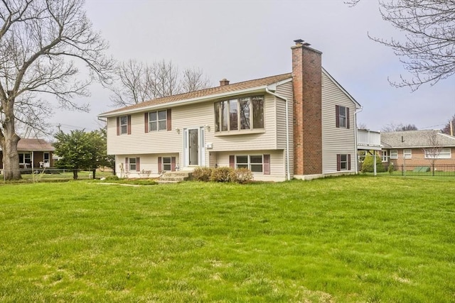 rear view of property with a lawn, fence, and a chimney