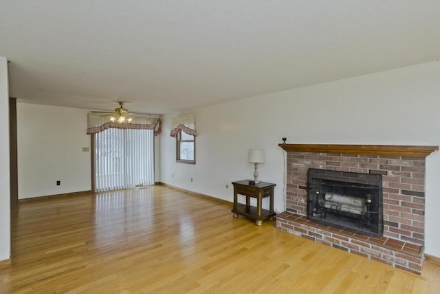 unfurnished living room featuring baseboards, a ceiling fan, a brick fireplace, and wood finished floors