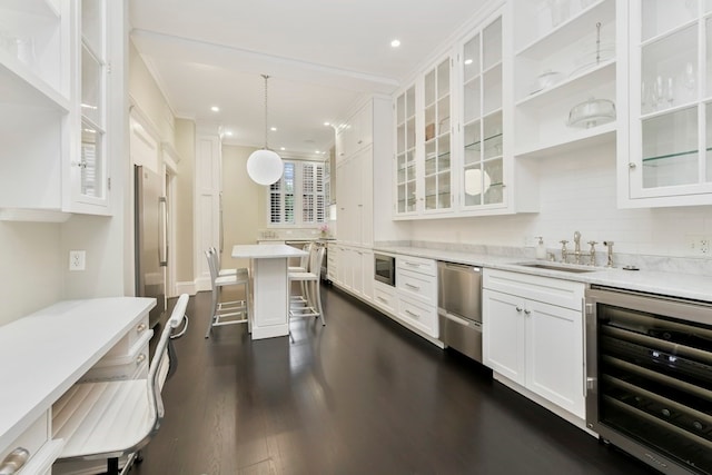 kitchen with a breakfast bar area, stainless steel appliances, white cabinetry, beverage cooler, and dark hardwood / wood-style flooring