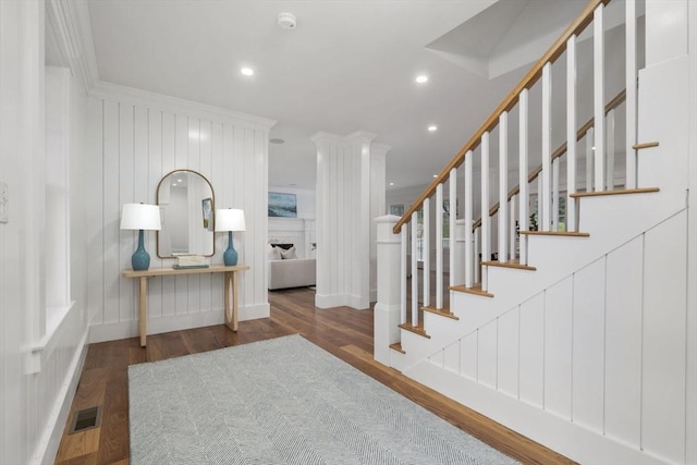 interior space with wood finished floors, visible vents, a fireplace, recessed lighting, and crown molding