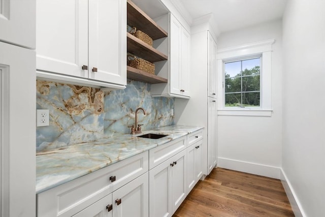 bar with tasteful backsplash, wood finished floors, baseboards, and a sink