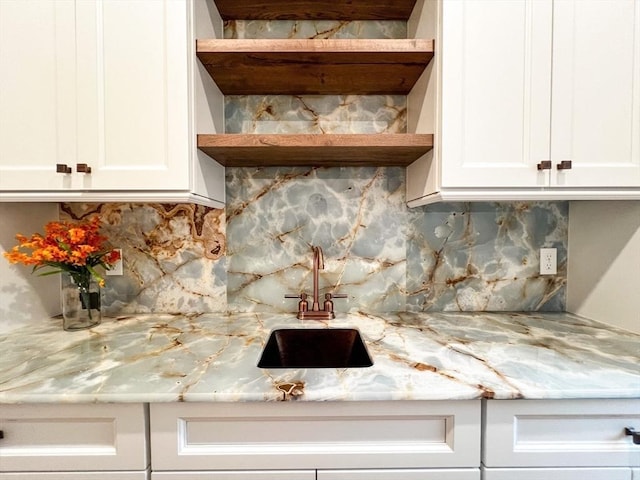 kitchen with light stone counters, open shelves, a sink, decorative backsplash, and white cabinets