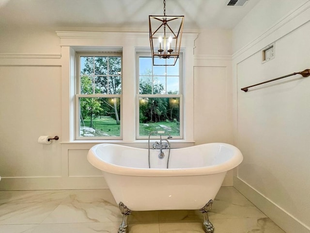 bathroom featuring visible vents, a soaking tub, marble finish floor, and a decorative wall