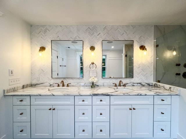 bathroom featuring double vanity, a stall shower, and a sink