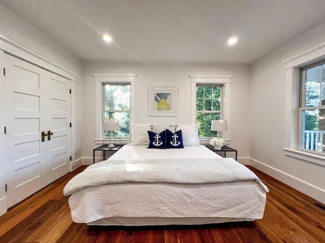 bedroom featuring baseboards, multiple windows, and dark wood-style flooring