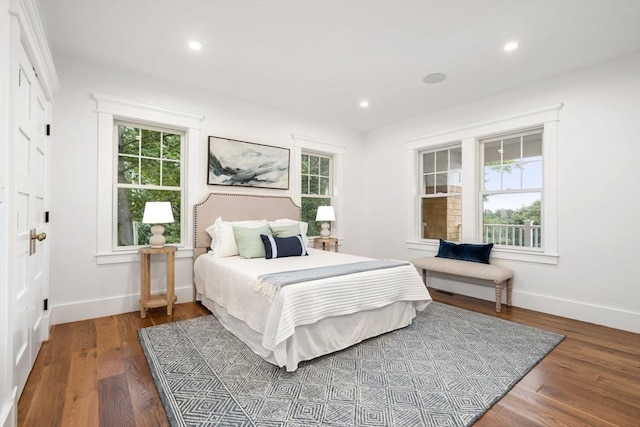 bedroom with baseboards, multiple windows, and wood finished floors