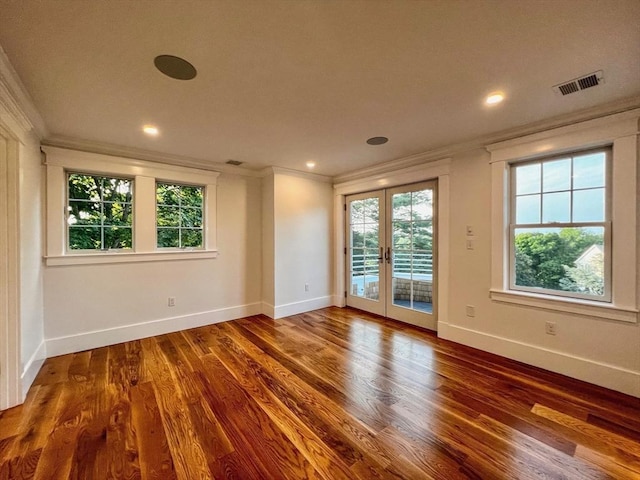 empty room with wood finished floors, french doors, visible vents, and ornamental molding