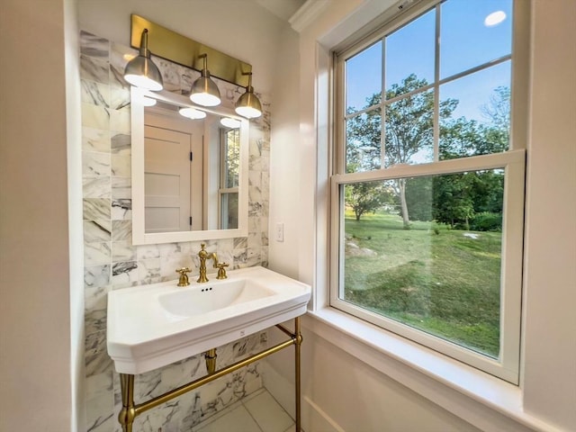 bathroom with a sink, backsplash, and a healthy amount of sunlight