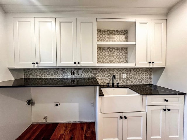 clothes washing area with a sink, electric dryer hookup, cabinet space, and dark wood-style floors